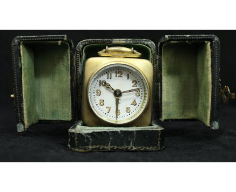 An early 20th Century French lacquered brass cased travel clock, the white enamelled dial with Arabic numerals, the movement 
