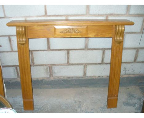A Modern oak fire surround with a central scrolling leaf crest.