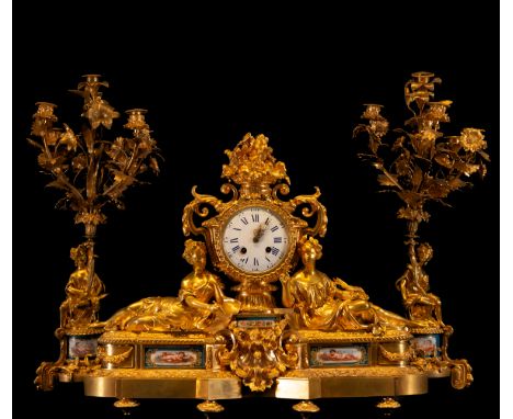 Gilded in very good condition, Paris machinery. Clock measurements: 65 x 20 x 55 cm, candlestick measurements: 70 x 30 x 30 c