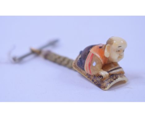 A Japanese carved ivory netsuke, in the form of a crouching man, inlaid with mother of pearl and stained decoration, signed, 