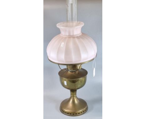 Early 20th century oil burner lamp having pink glass fluted shade above a brass reservoir and base.  (B.P. 21% + VAT)