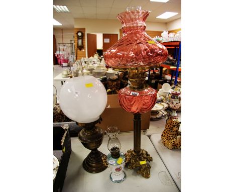 ANTIQUE OIL LAMP with cranberry glass reservoir and shade on a scroll gilt-metal base and with Corinthian column together wit