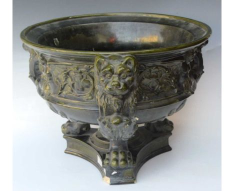 A large dark green glaze pottery bowl or planter, possibly Continental, raised on triform lion's mask monopod supports, impre
