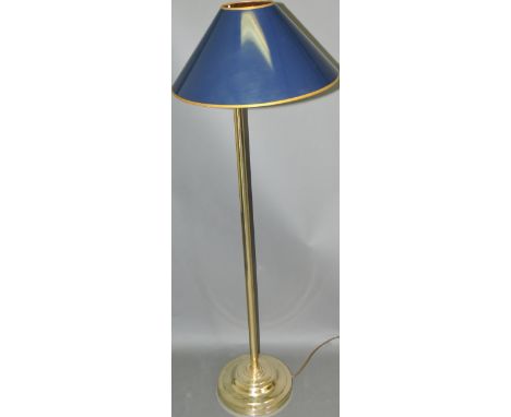 A brass standard lamp by Christopher Wray, the lamp with a blue paper shade on an articulated arm, with a circular weighted b