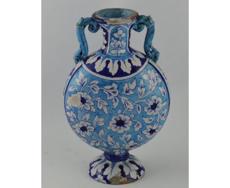 An Iznik style pottery two handled moon flask vase, the turquoise blue glazed body decorated with flowerheads and leaves on a