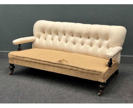 A late Victorian ebonised button back sofa, the rectangular button back over padded arms with turned baluster supports on tur