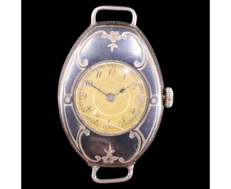 An early 20th Century lady's niello and silver wristlet watch, having a circular champagne face within a scroll-and-blossom d