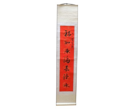 A Chinese calligraphic hanging scroll, each character atop a gilt dragon-and-fenghuang medallion, set against a scarlet backg