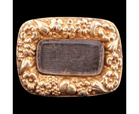 A Victorian gold mourning locket brooch, incorporating a central field of hairwork under bevel-edged glass within a relief ac