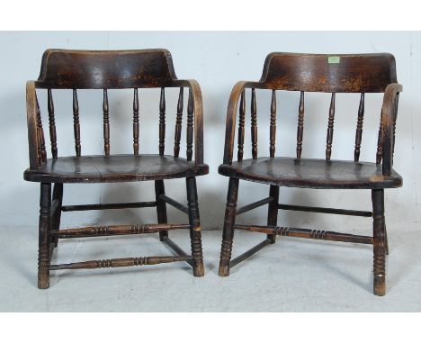 A pair of early 20th century Edwardian 1920's Smokers Bow oak chair / armchairs. The chairs having curved top rail with turne