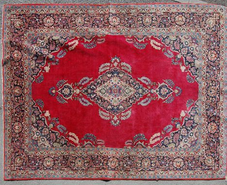 A mid 20th century Persian Islamic Sarouk handwoven wool carpet rug having foliate decoration to the red field with multicolo