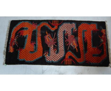 A decorative vintage 20th century handwoven Tibetan rug having a repeating polychrome dragon motif having tassels to each end