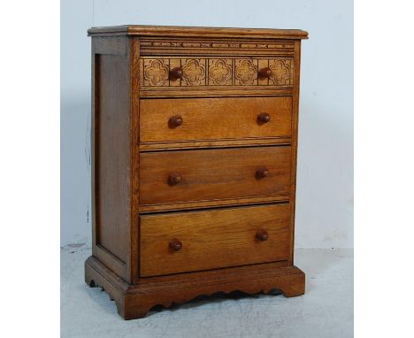 An early 20th century Arts and Crafts oak bedside cabinet having a flared top over quatrefoil motif decoration atop a bank of