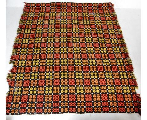 A large vintage 20th century woollen Welsh blanket having a red background with yellow and orange geometrics patterns through