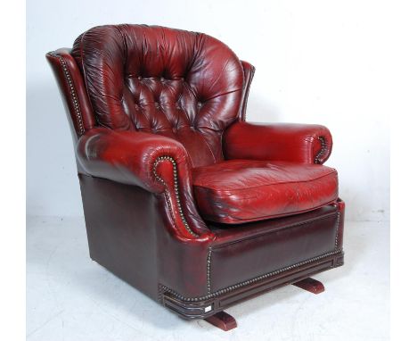 A 20th Century Chesterfield armchair / rocking chair upholstered in red oxblood leather with a button back backrest and rivet