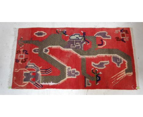 A decorative vintage 20th century handwoven Tibetan rug having red background with a large stylised polychrome dragon and tas