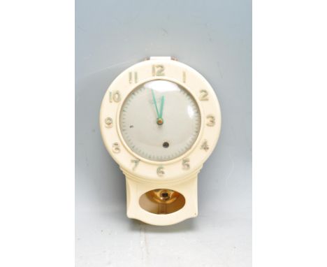 A vintage 20th century cream bakelite wall mounted clock by Smiths of Enfield having a white enamel face with arabic numerals