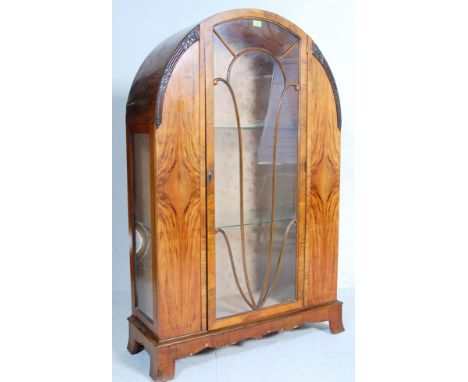 An early 20th century circa 1920’s Art Deco walnut china display cabinet. The pedestal cabinet having dome top with single ga