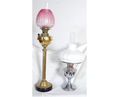 A Victorian 19th century oil lamp by Youngs Central Draft having a cranberry glass shade with floral decoration with a brass 