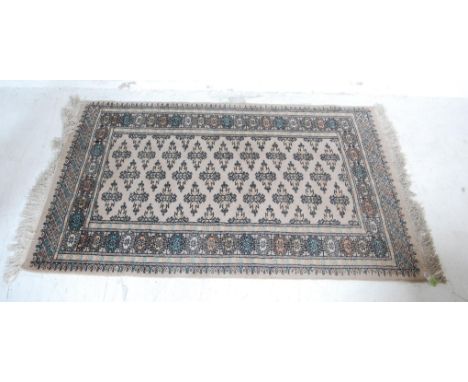 A vintage 20th century Persian Islamic rug having a cream background with a large central field decorated with geometric moti