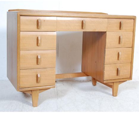 An early 20th century Art Deco walnut pedestal desk having chamfered edges over a large central drawer flanked by banks of fo