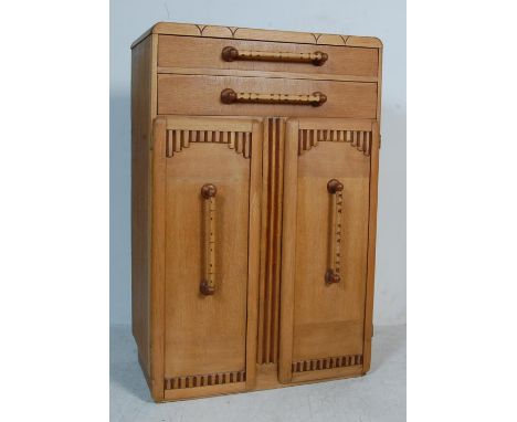 An early 20th century 1930s Art Deco golden oak tallboy chest of drawers having a carved front over a bank of two drawers wit