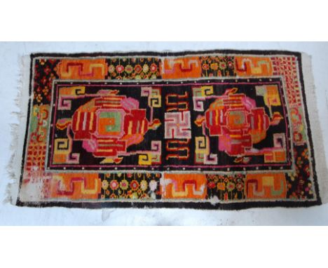 A decorative vintage 20th century handwoven Tibetan rug having vibrantly coloured yin and yang motifs set within a border dec
