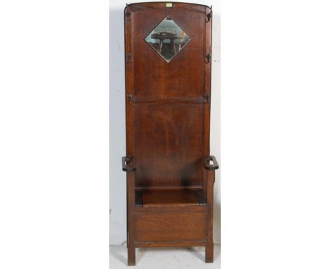 A vintage mid 20th century oak hall stand having a lozenge shaped mirror flanked by coat / hat hooks. The hall stand has a se