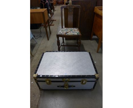 A metal steamer trunk and an oak dining chair 