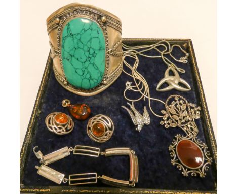 A selection of costume jewellery to include brooches, bracelet amber, a large distinctive bangle etc 