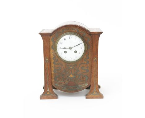  An oak mantle clock probably retailed by Liberty & Co, the rounded rectangular body supported on four pillar feet, inlaid wi