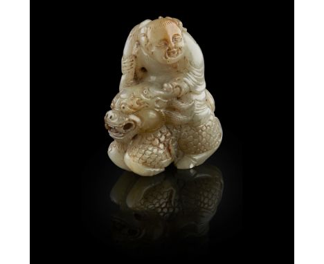 JADE CARVING OF THE LOTUS BOY ON A QILIN  the boy shown atop a recumbent qilin, holding a branch of lotus, the face with jovi