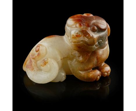CELADON AND RUSSET JADE FIGURE OF A BUDDHIST LION CUB  the mythical lion shown in a recumbent position with head turned sidew