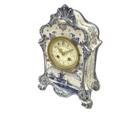 An early 20th century Delft china mantel clock, with 8 day barrel movement striking on a bell, the case moulded with shell an