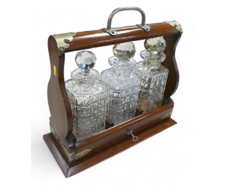 An oak three decanter tantalus, 37 by 15 by 36cm high. 