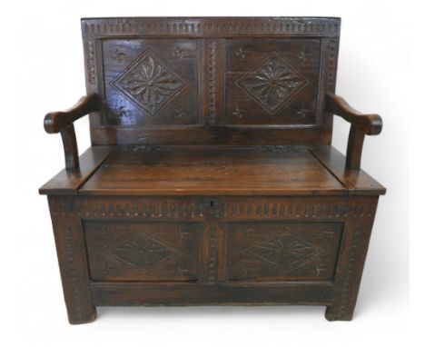 An oak hall bench with a carved panel back and lift up seat, 106 by 57 by 105cm high. 