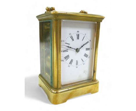 A brass carriage clock, striking on a gong, 8 by 7 by 12cm high with handle down, with key and running. 