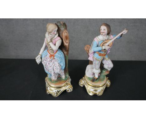 Two hand painted porcelain figures on scrolling design stands, one of a gentleman playing a lute and the other a young female