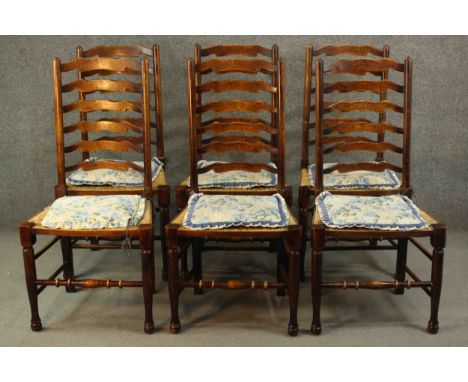 A set of six country oak ladder back dining chairs, with rush seats, on turned legs joined by turned stretchers. 