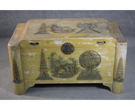 A 20th century Chinese yellow painted camphorwood trunk, decorated to the top and front wth a pagoda and other buildings. H.5