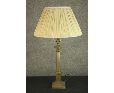 A 20th century brass Corinthian column table lamp, on a square step down plinth base, with an ivory coloured pleated shade. H