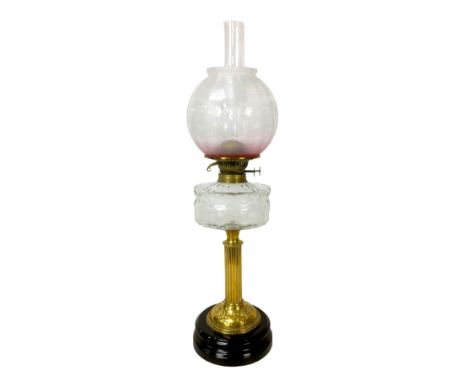 A Victorian paraffin lamp, with clear glass reservoir on a brass column, etched glass globe shade and chimney, overall 17 by 