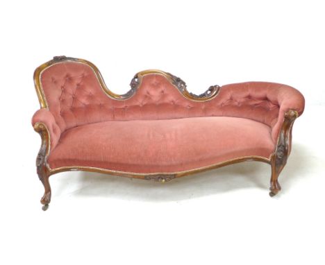 A Victorian walnut framed settee, covered in a pink button back dralon fabric, raised on cabriole legs and castors, 220 by 48