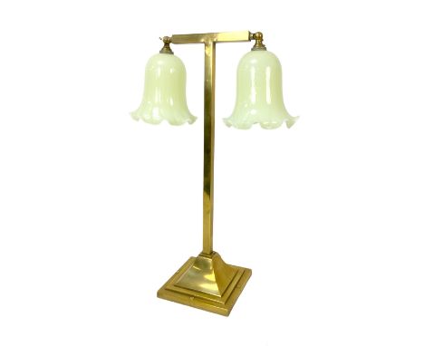 An Edwardian brass table lamp, with twin harebell-shaped lemon yellow opalescent shades issuing from a T-shaped frame, in nee