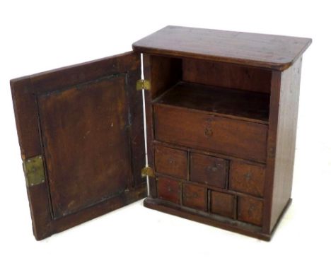 An oak table top cabinet, single panel door opening to reveal a shelf and eight fitted trinket drawers, 40 by 22 by 48cm high