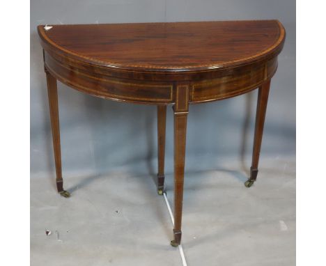 An Edwardian inlaid mahogany card table, raised on tapered legs and castors 