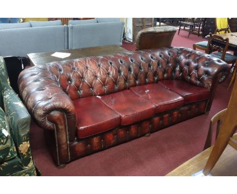 A Chesterfield button back red leather sofa, on bun feet,  with associated cushions, H.72 W.240 D.97cm 