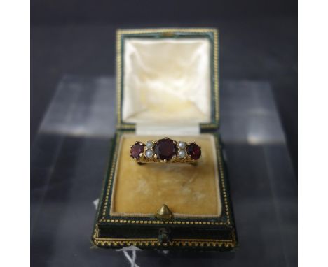 A 9ct yellow gold, three stone ruby and seed pearl set ring, hallmarked, size R, in associated case 