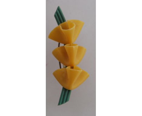 A 1930's Art Deco Bakelite green bar brooch with three yellow lilies and safety pin clasp. Measures 5cms.