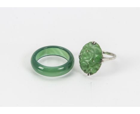 A vintage Chinese jade and white metal ring, together with a green hardstone band ring (2)The carved hardstone band ring is n